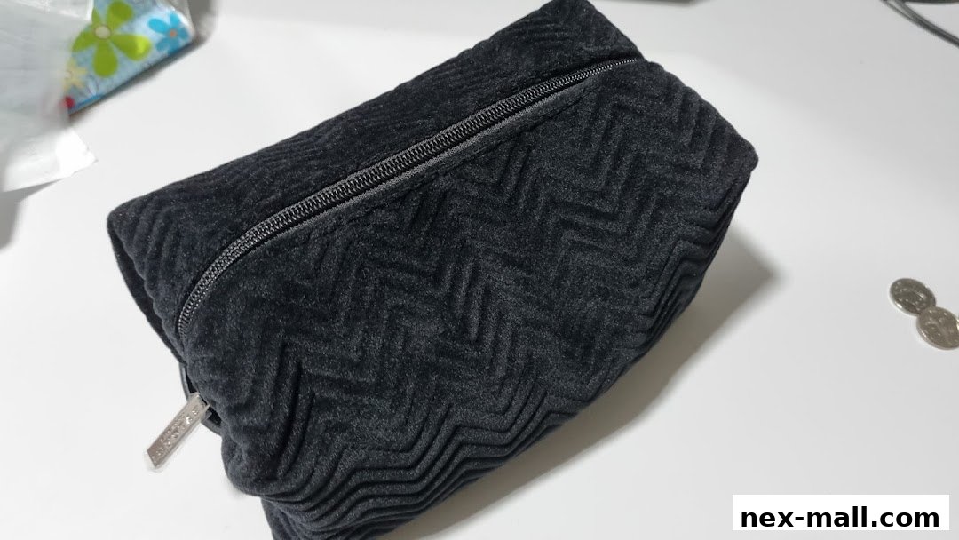 A textured black makeup bag with a zipper and a silver logo tag.