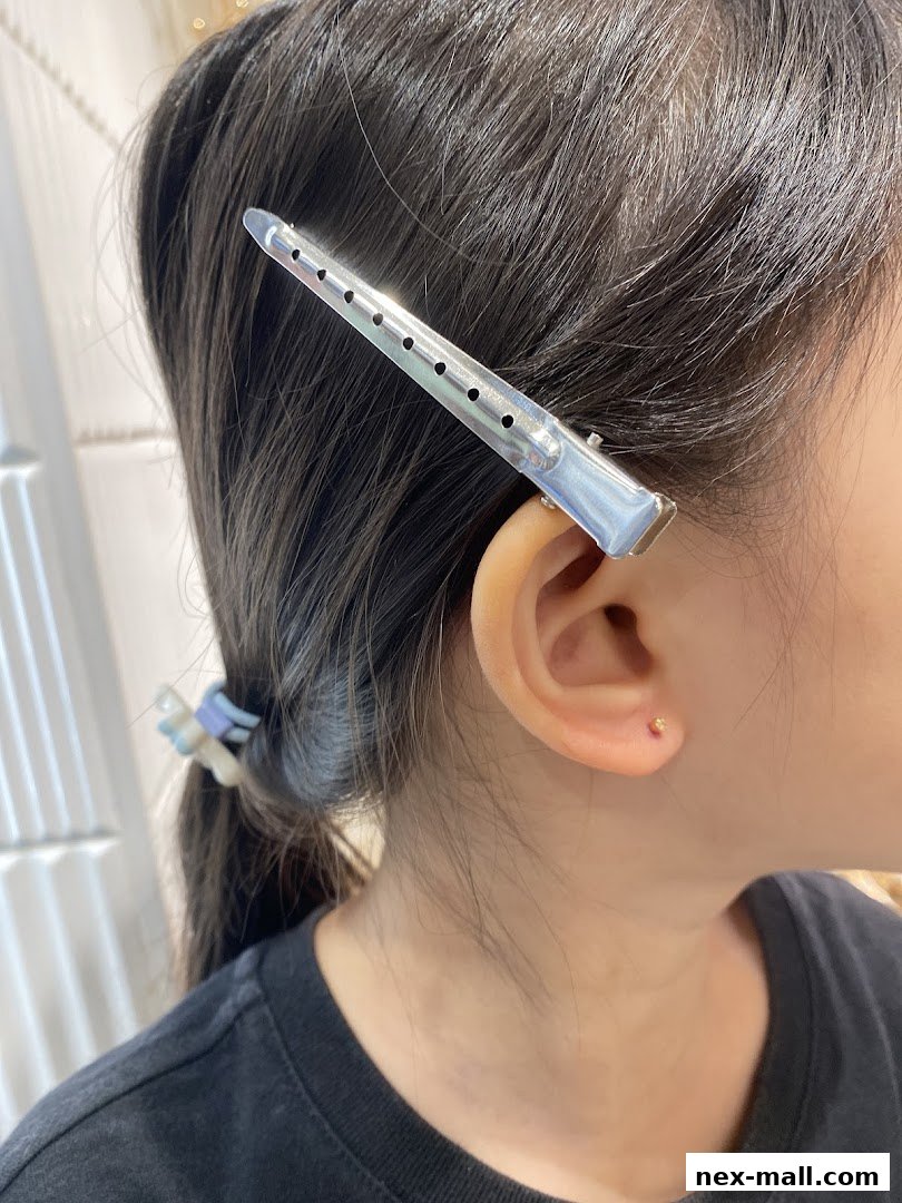 Close-up of a person's ear with a small stud earring and a hair clip.
