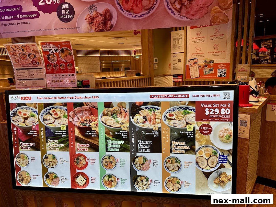 A brightly lit digital menu board showcasing various ramen dishes and set meals.
