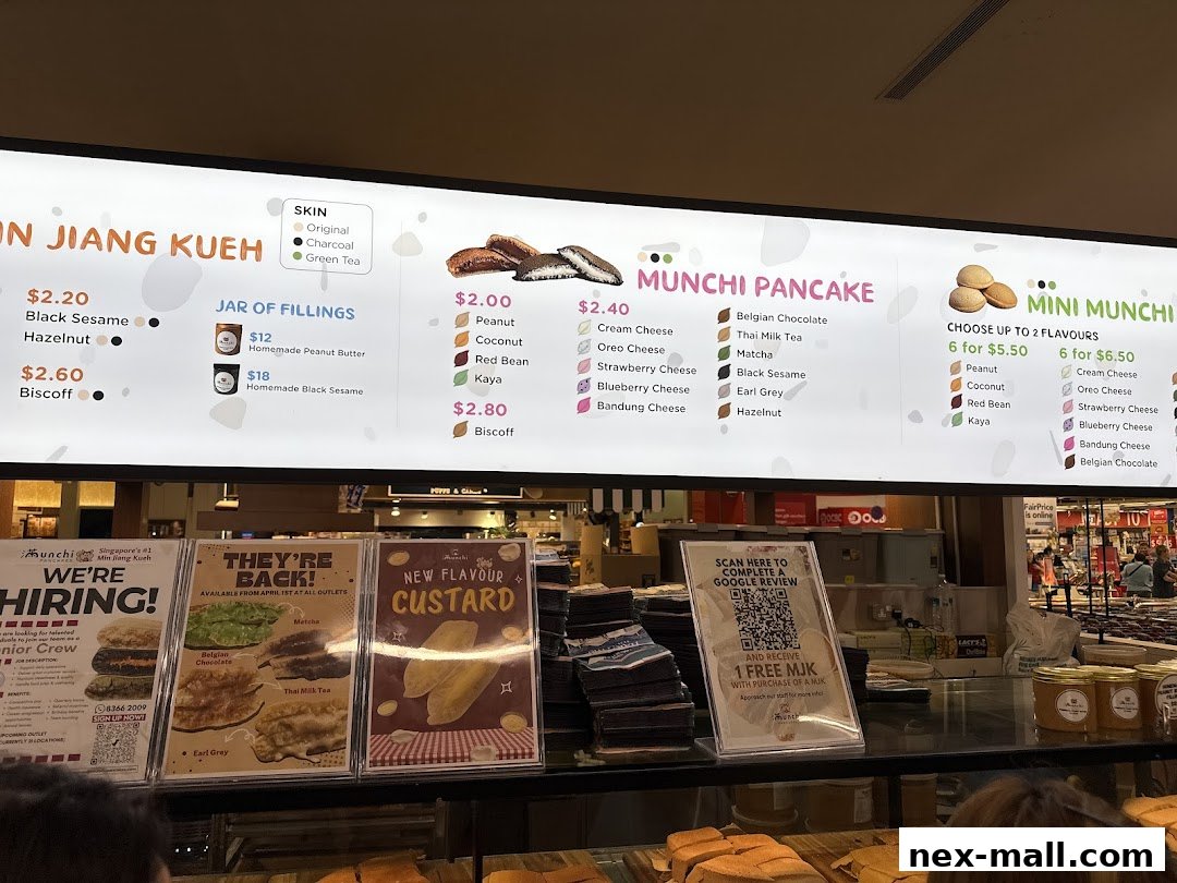 A brightly lit menu board displaying various pancake and kueh flavors and prices.