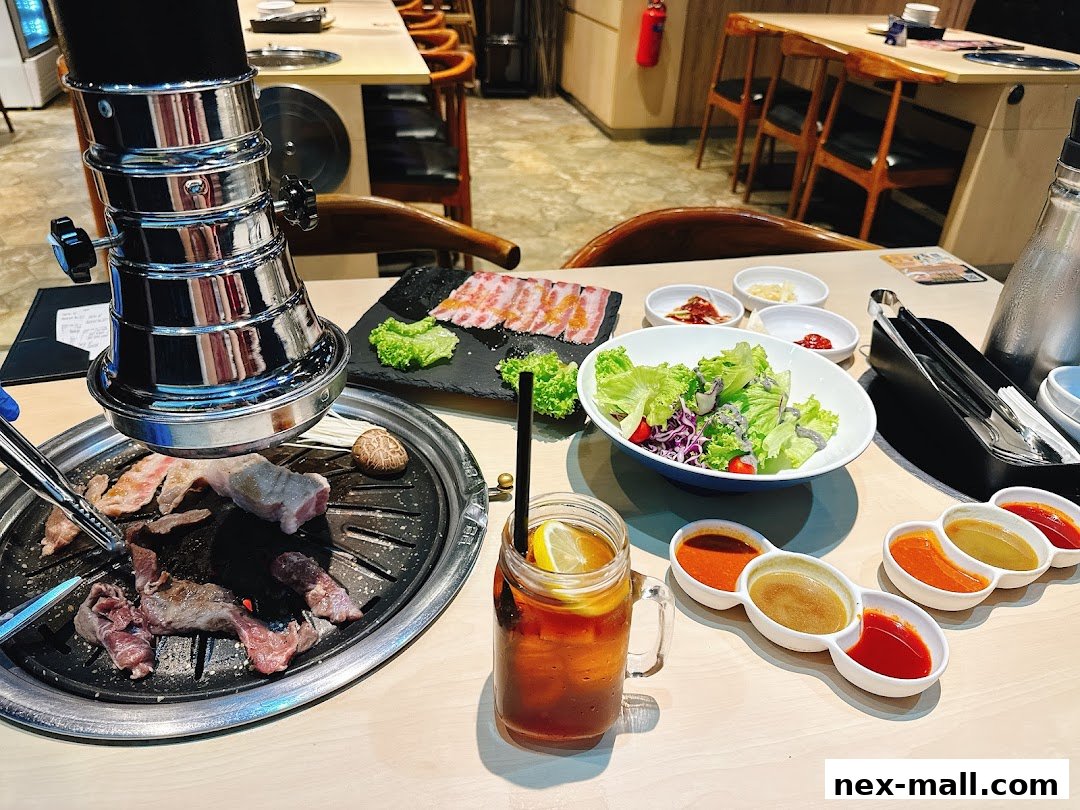 A table set for Korean BBQ with grilled meats, salad, sauces, and iced tea.