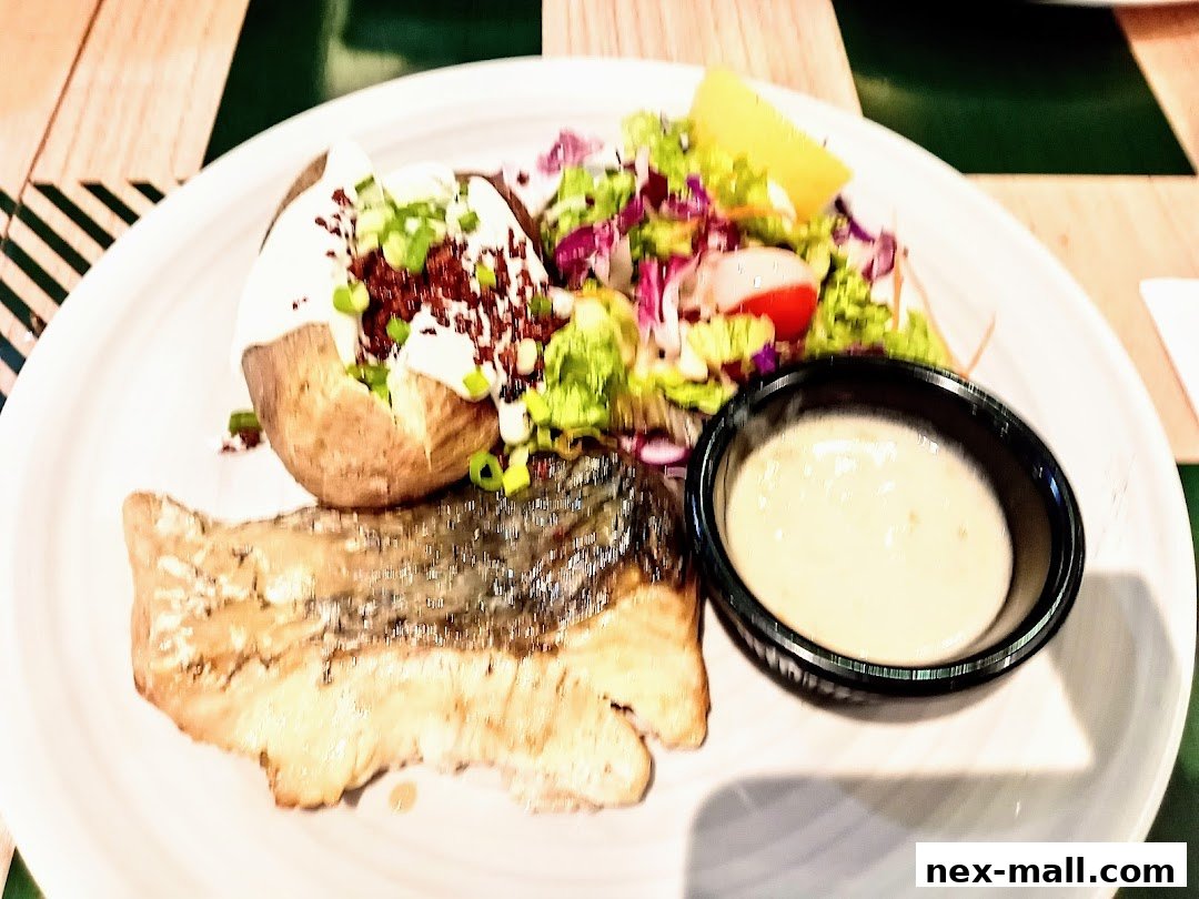 A plate of grilled fish with a baked potato, salad, and dipping sauce.