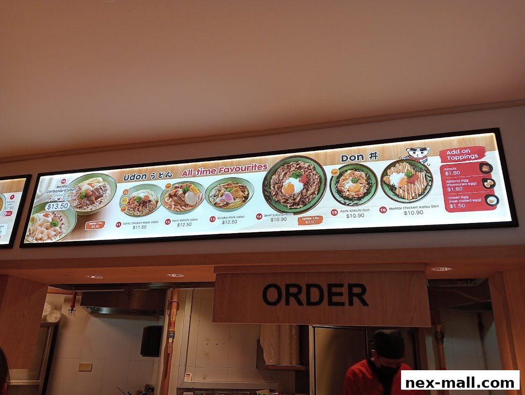 A brightly lit menu board showcasing various udon and donburi dishes with prices.