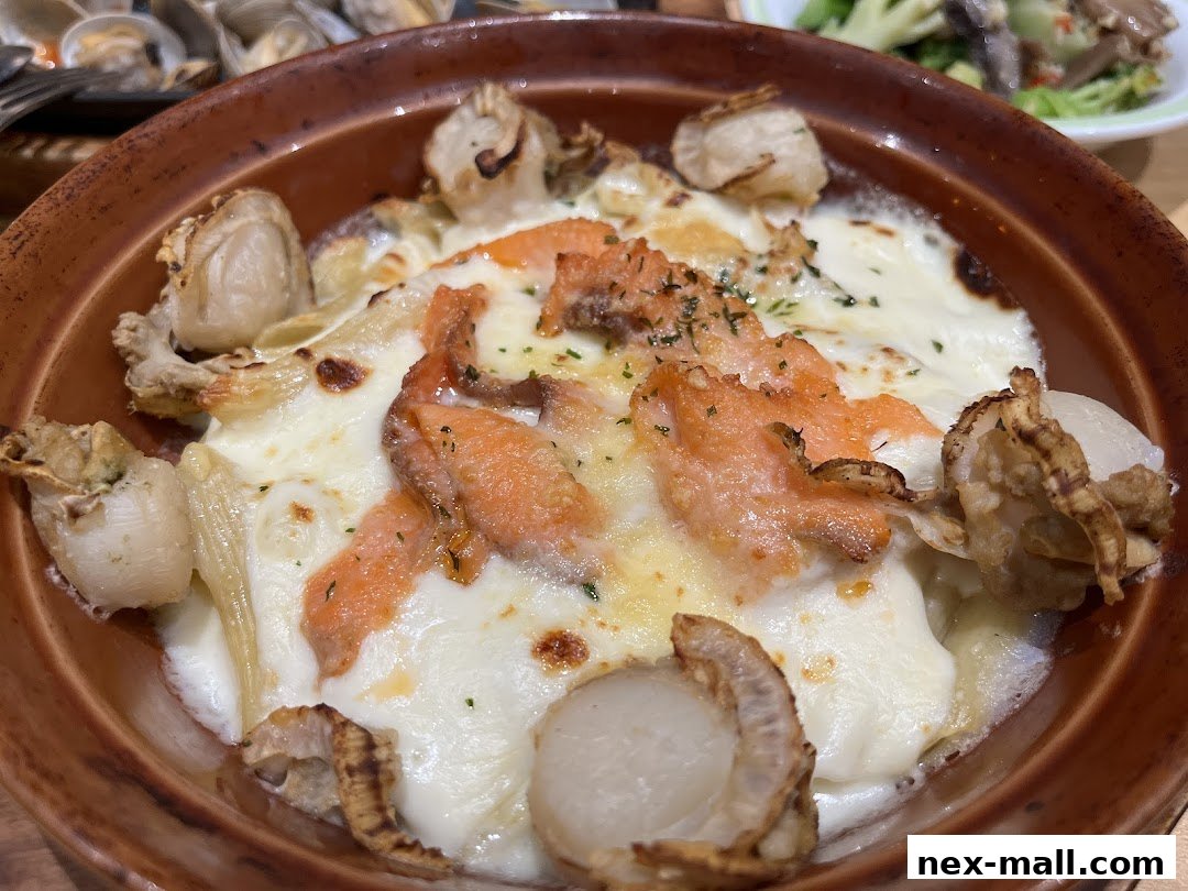 A close-up of a baked dish with salmon, scallops, and melted cheese in a brown ceramic bowl.