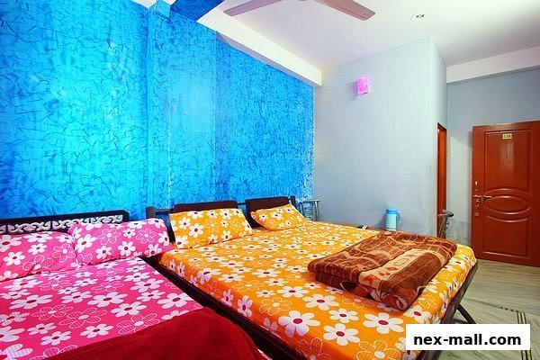 A hotel room with two beds, one with pink floral bedding and the other with orange floral bedding.