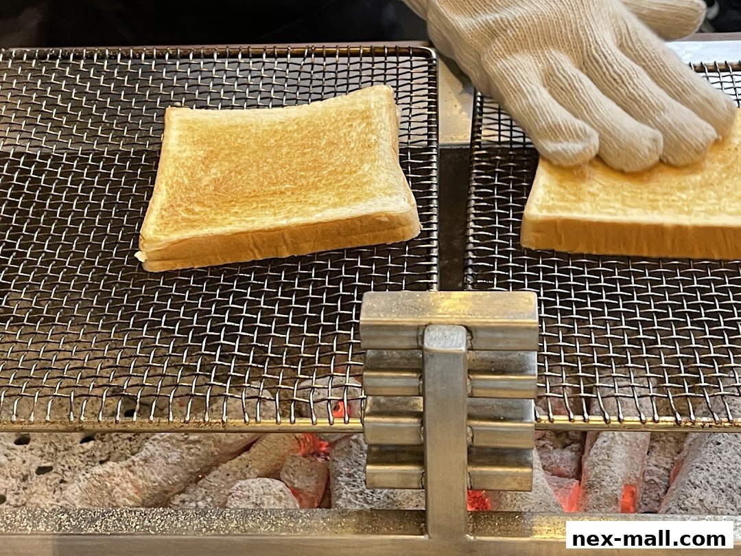 A gloved hand places slices of bread on a wire rack over glowing coals.