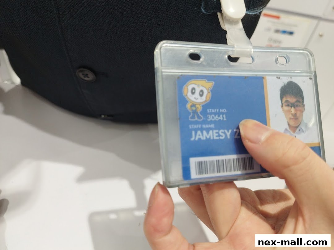 A hand holds an employee ID badge with a photo and name.