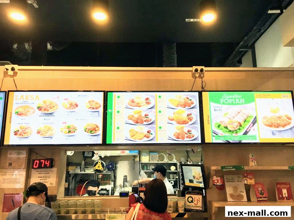 Digital menu boards displaying various Laksa and Popiah dishes at Qi Ji.