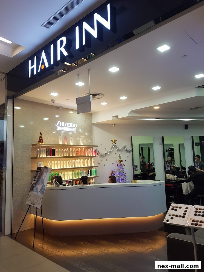 The entrance of Hair Inn salon with a reception desk, product shelves, and stylists working.