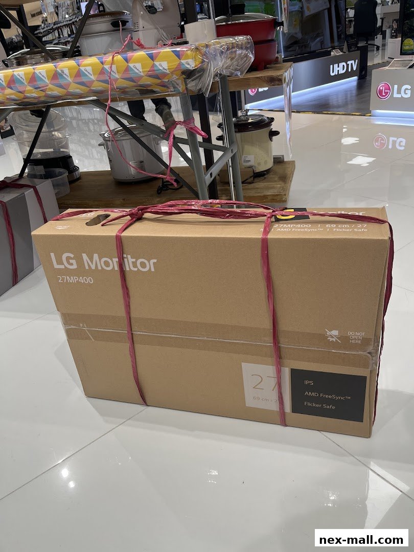A boxed LG monitor is displayed in a retail store with other appliances.