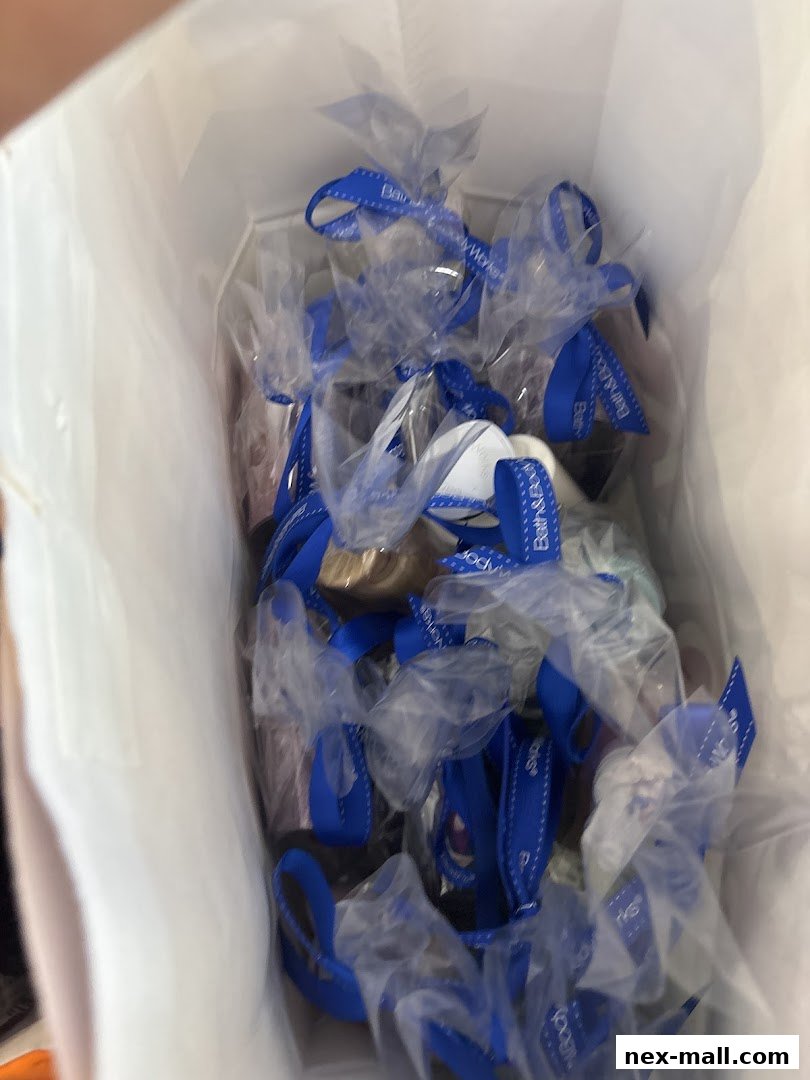 A white shopping bag filled with Bath & Body Works products tied with blue ribbons.