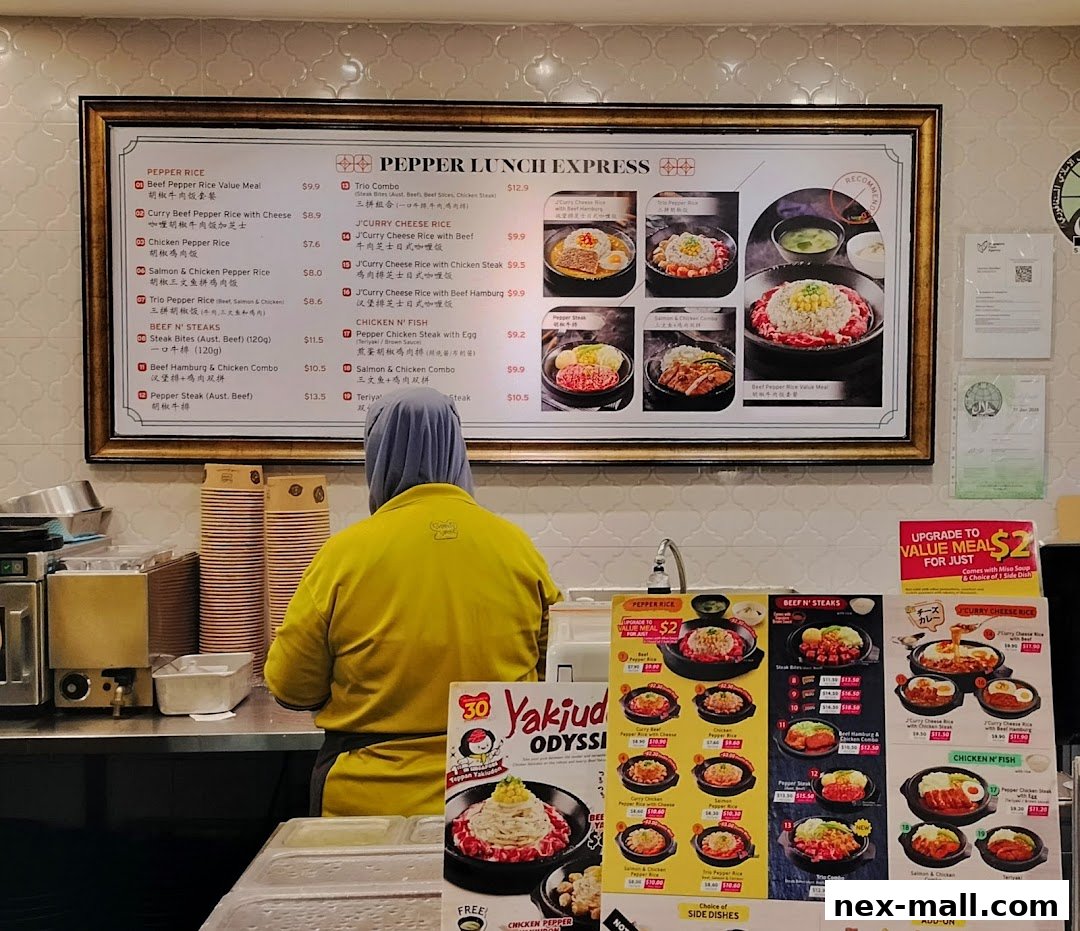 A person in a yellow shirt stands at a counter with a menu board and promotional flyers.