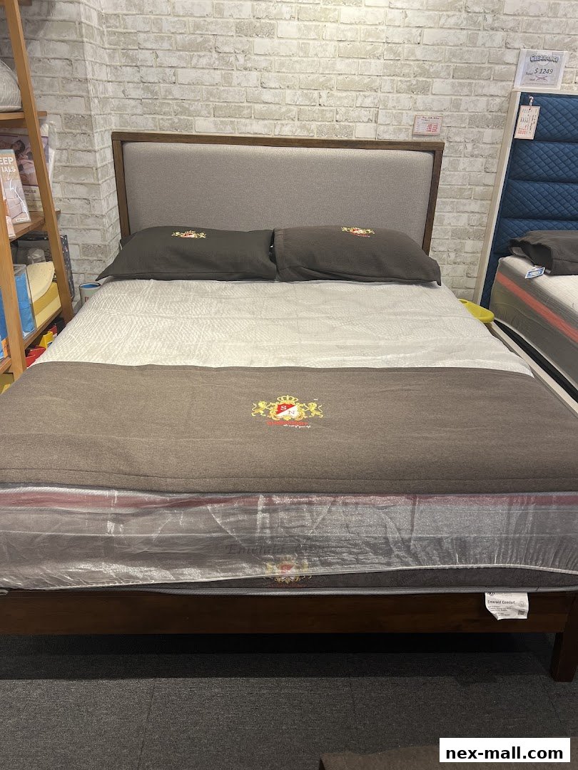 A beautifully made bed with a wooden frame, grey headboard, and plush bedding.