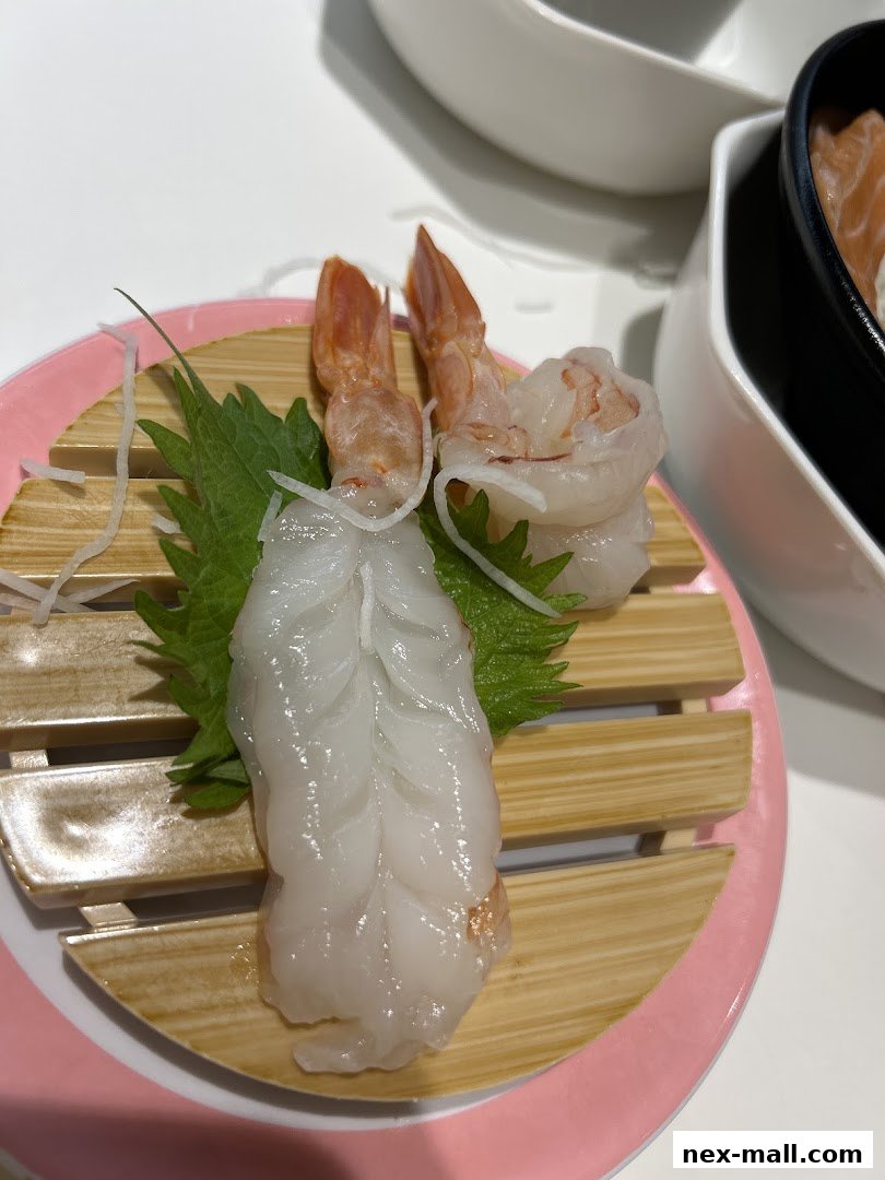 Close-up of fresh sushi with shrimp and white fish on a wooden plate.