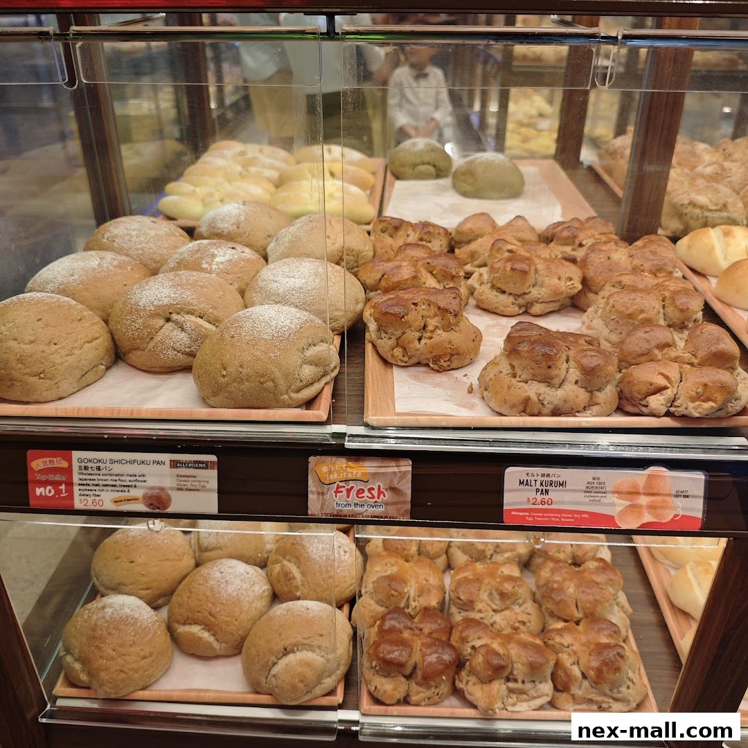 A display case filled with various types of freshly baked Japanese bread and pastries.