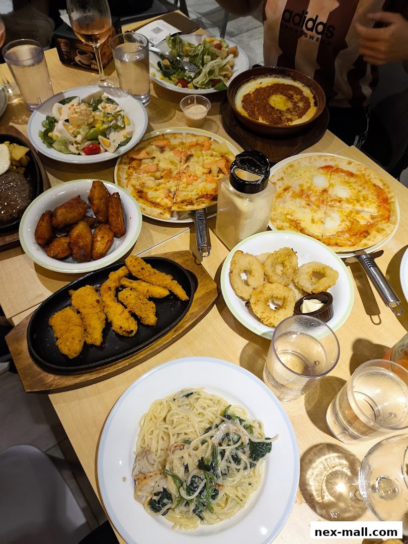 A table laden with various Italian dishes including pizza, pasta, fried chicken, and salads.