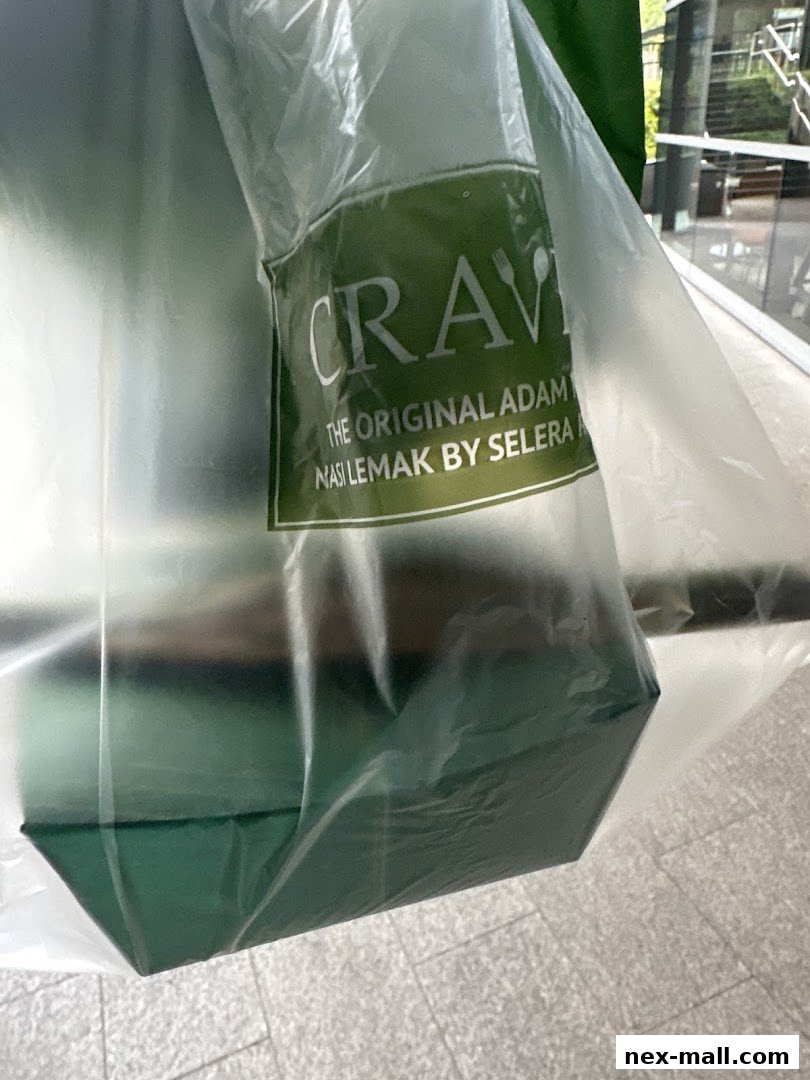 A plastic bag with the Crave Nasi Lemak logo containing food.