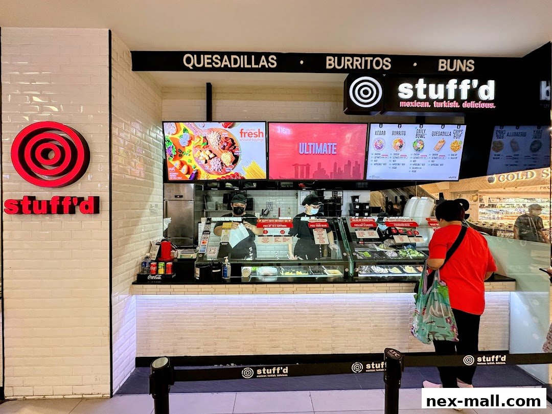 A Stuff'd shop counter with staff serving customers and a menu board displaying food options.