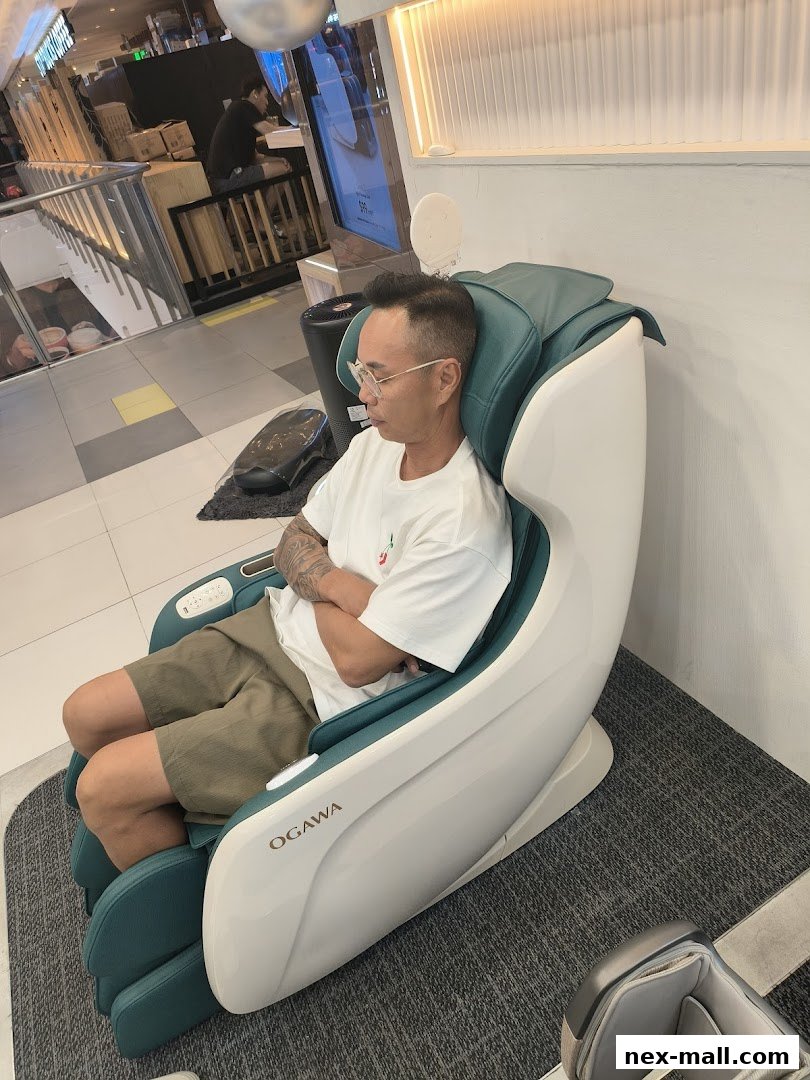 A man sits in a modern OGAWA massage chair, experiencing relaxation.