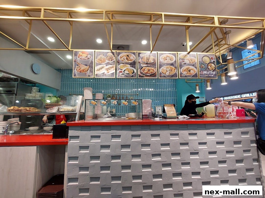 A food counter with staff serving customers and menu displays above.