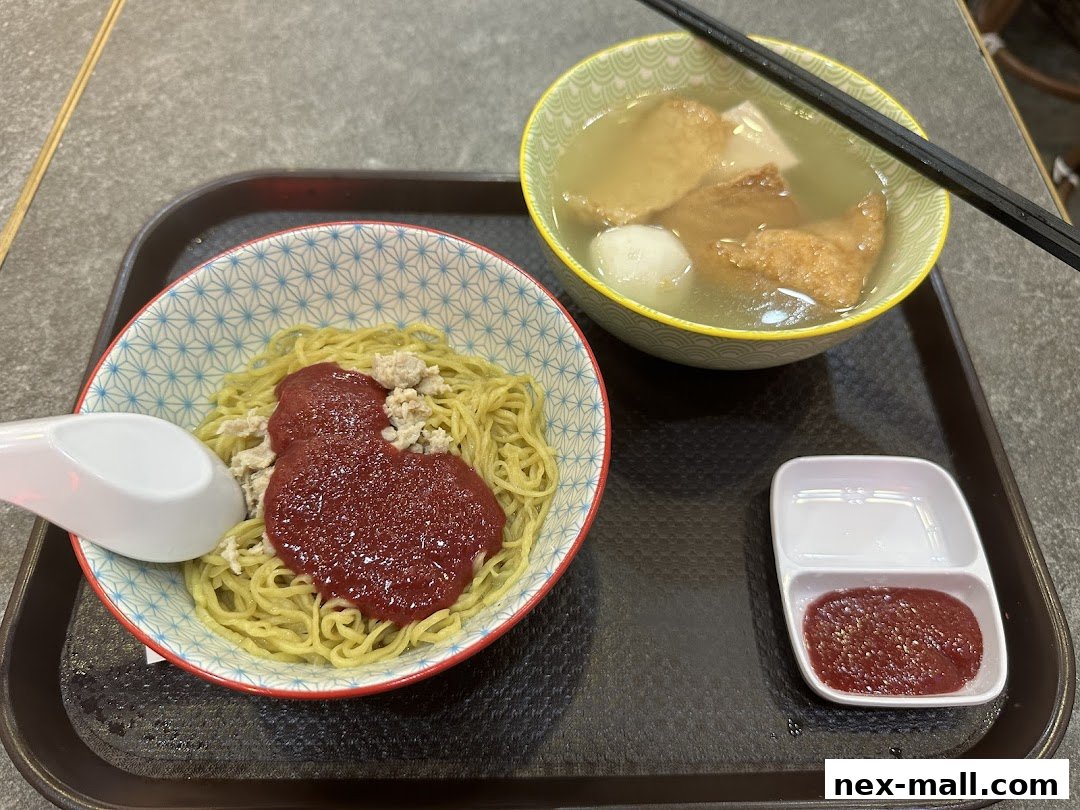 A bowl of noodles with minced meat and sauce, served with a side of soup and dipping sauce.