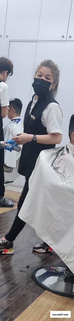 A hairdresser wearing a mask cuts a child's hair in a salon.
