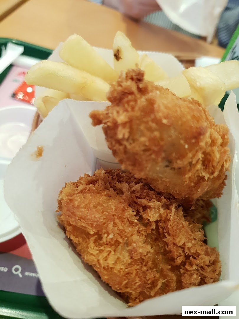 A close-up shot of MOS Burger's crispy fried chicken and fries, served in paper packaging.