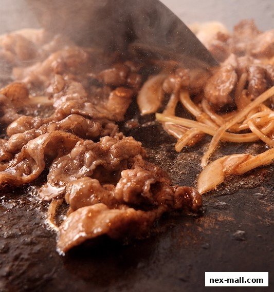 Sizzling beef and onions being cooked on a hot plate, creating a mouthwatering dish.
