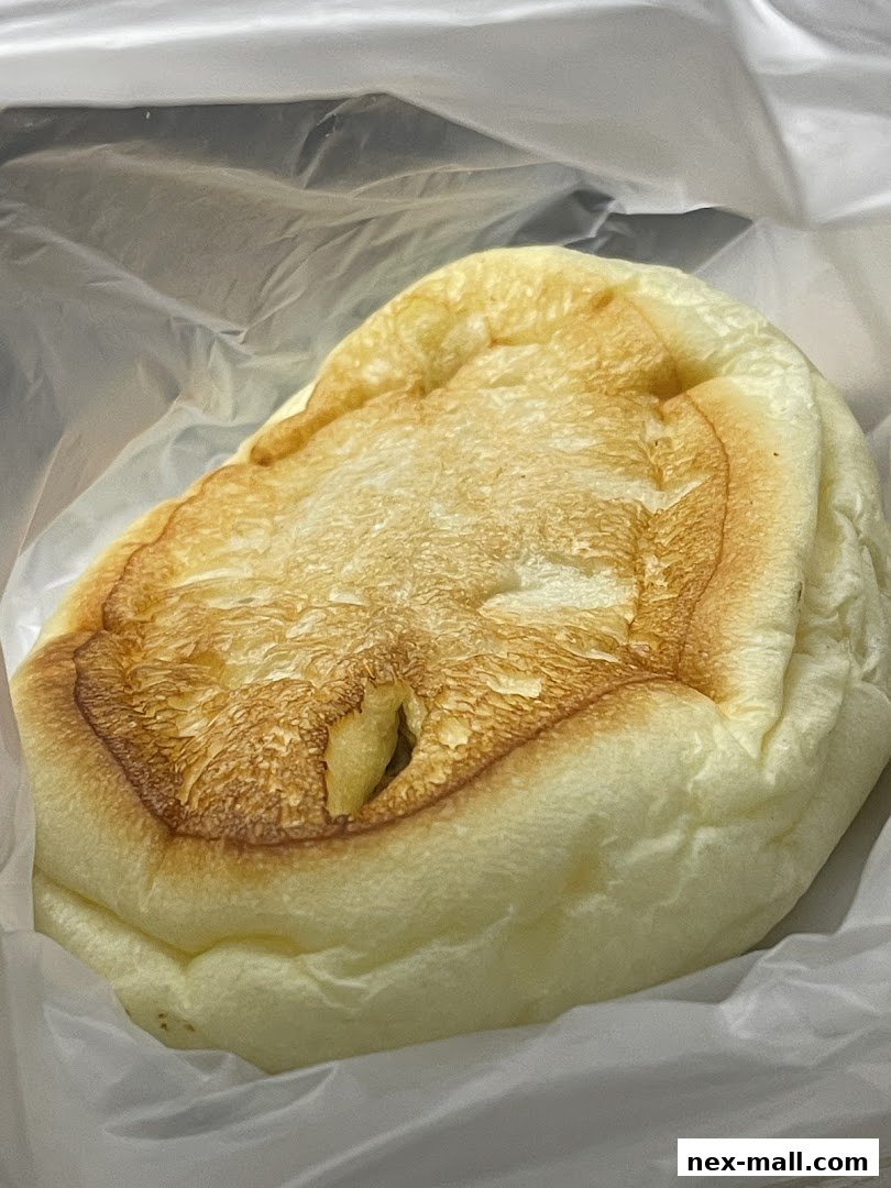 A close-up of a fluffy, golden-brown Japanese bread in a plastic bag.