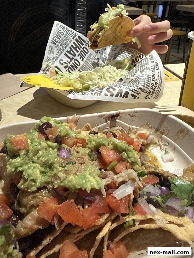 A close-up of delicious Mexican food, including nachos and a taco, served in branded packaging.