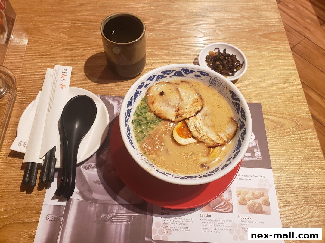 A bowl of ramen with pork slices, egg, and broth, served with chopsticks and a drink.