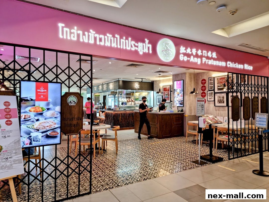 The entrance of Go-Ang Pratunam Chicken Rice, a restaurant with a pink facade and a display of their signature dish.
