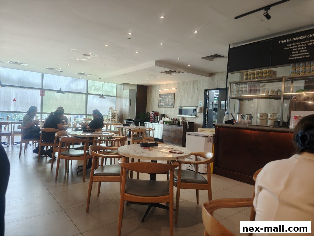 Interior of a restaurant with customers dining at tables and a counter with food items.