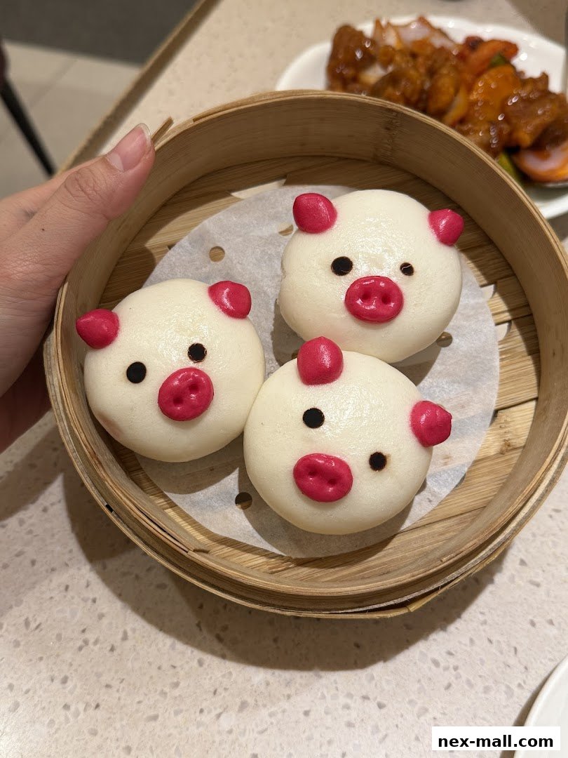 Three adorable steamed buns shaped like pigs in a bamboo steamer.