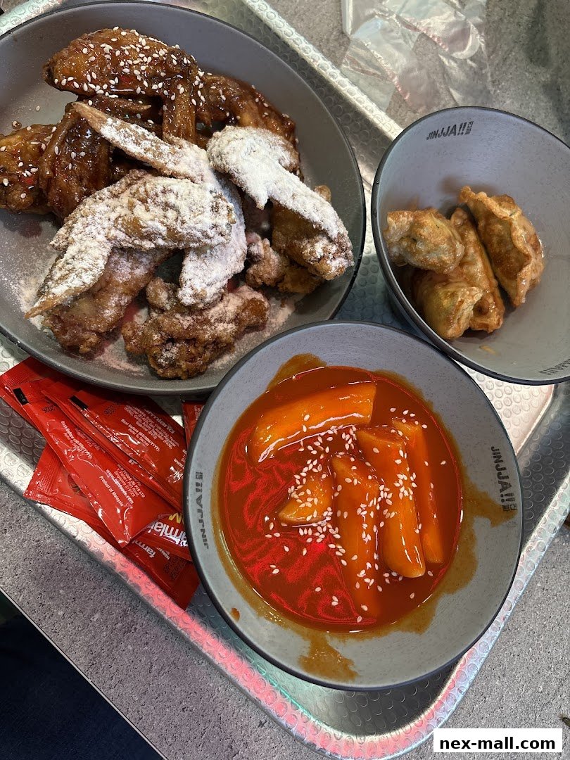 A close-up shot of Korean fried chicken, tteokbokki, and dumplings served on a tray.