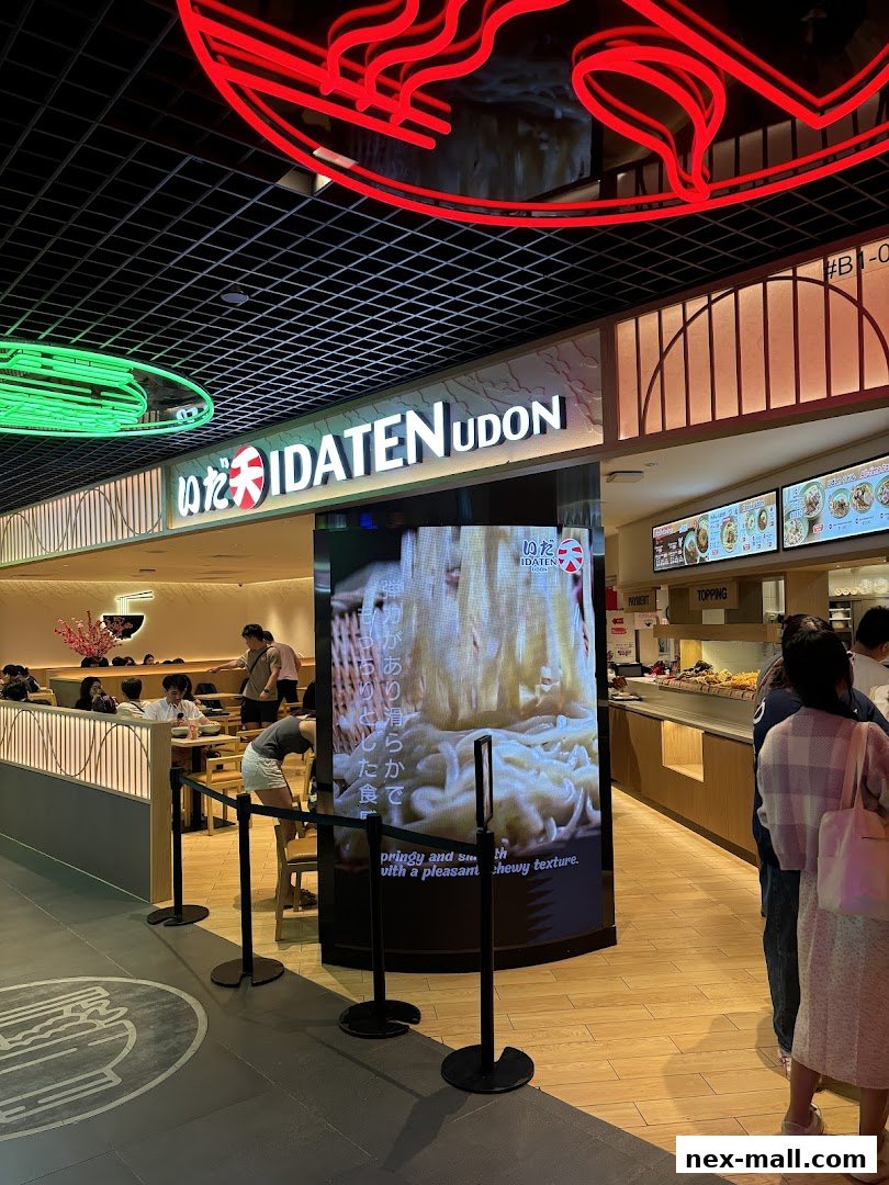 The entrance of Idaten Udon with a large digital display showcasing udon noodles.