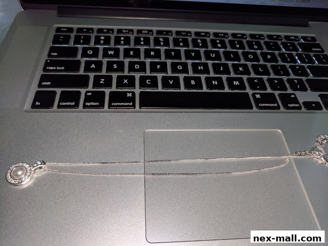 A pearl and diamond pendant necklace rests on a laptop keyboard.