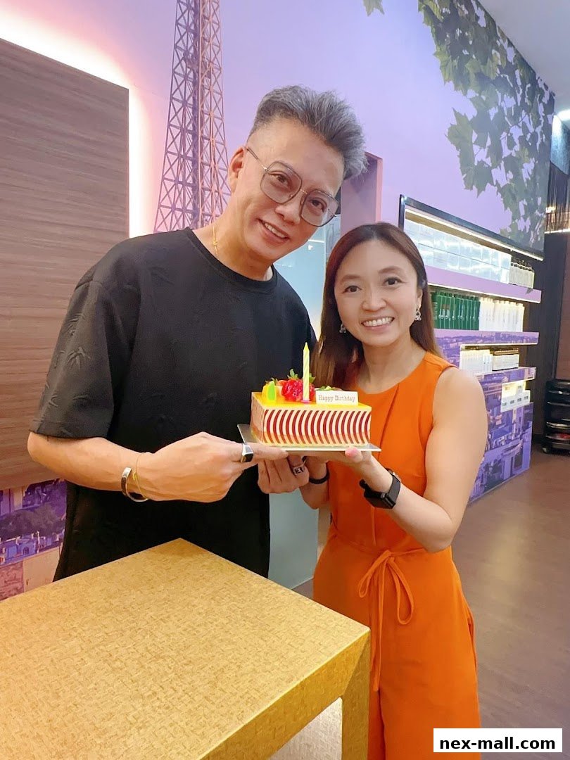 Two people smiling and holding a birthday cake with 'Happy Birthday' written on it.