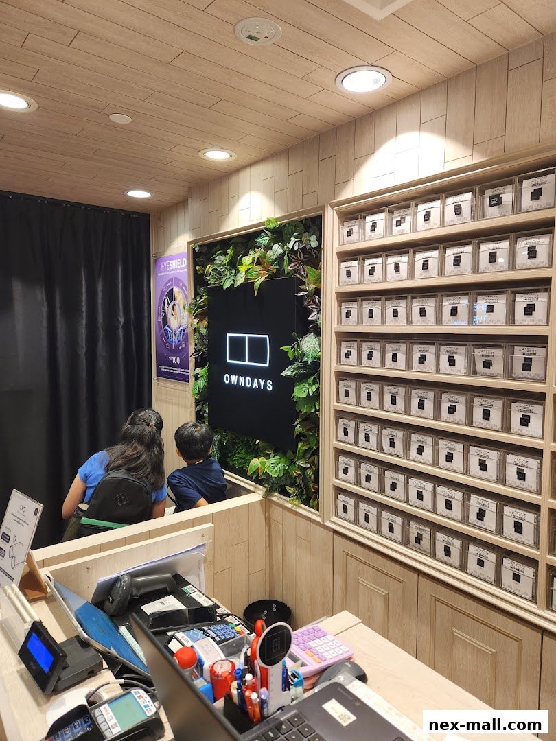Interior of an OWNDAYS optical shop with customers and display shelves of glasses.