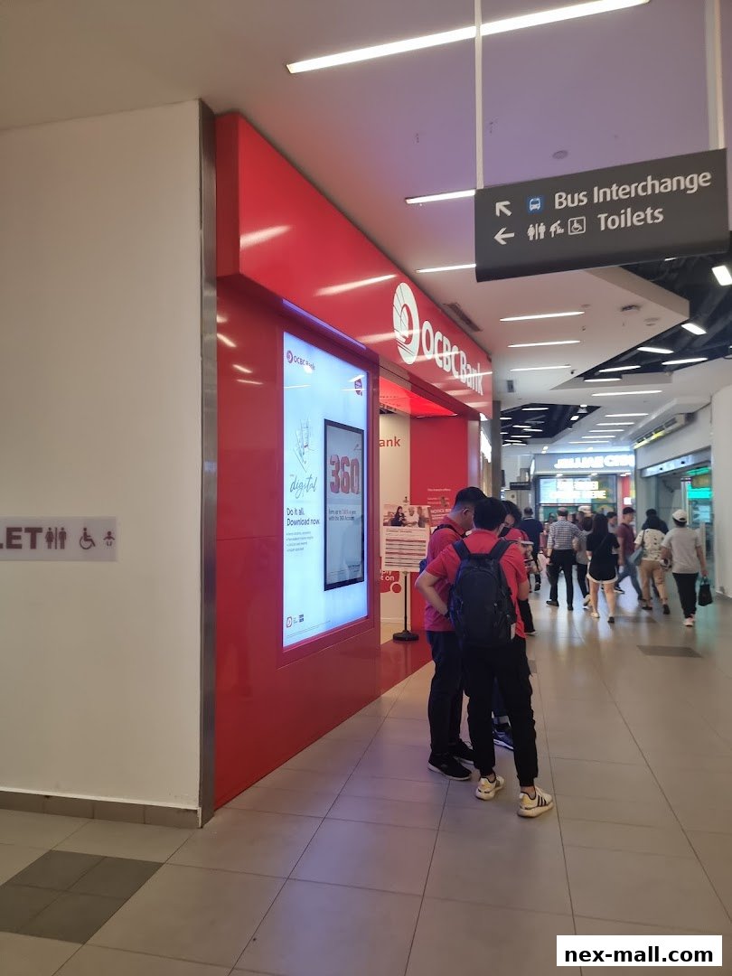 The exterior of an OCBC Bank branch with a digital display and people walking by.