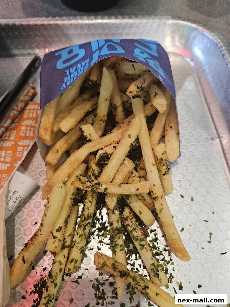 A close-up shot of seasoned french fries served in a branded paper container.