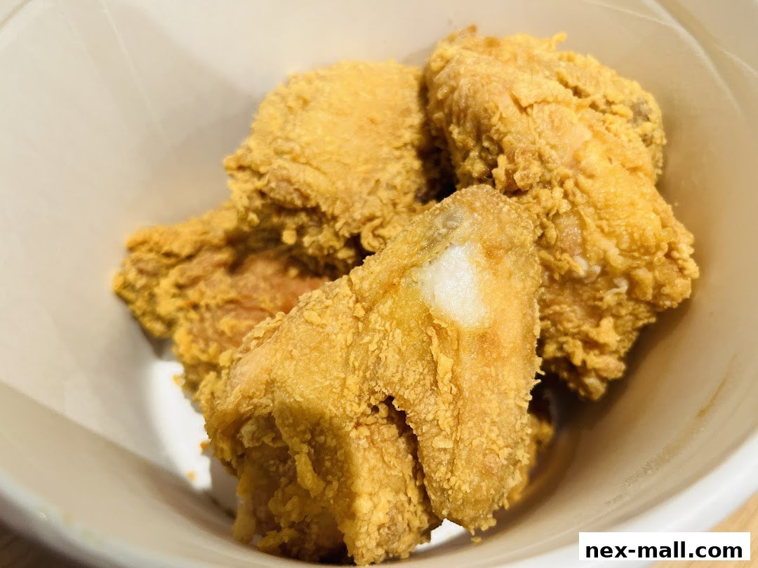 A close-up shot of crispy, golden-brown fried chicken pieces in a white container.