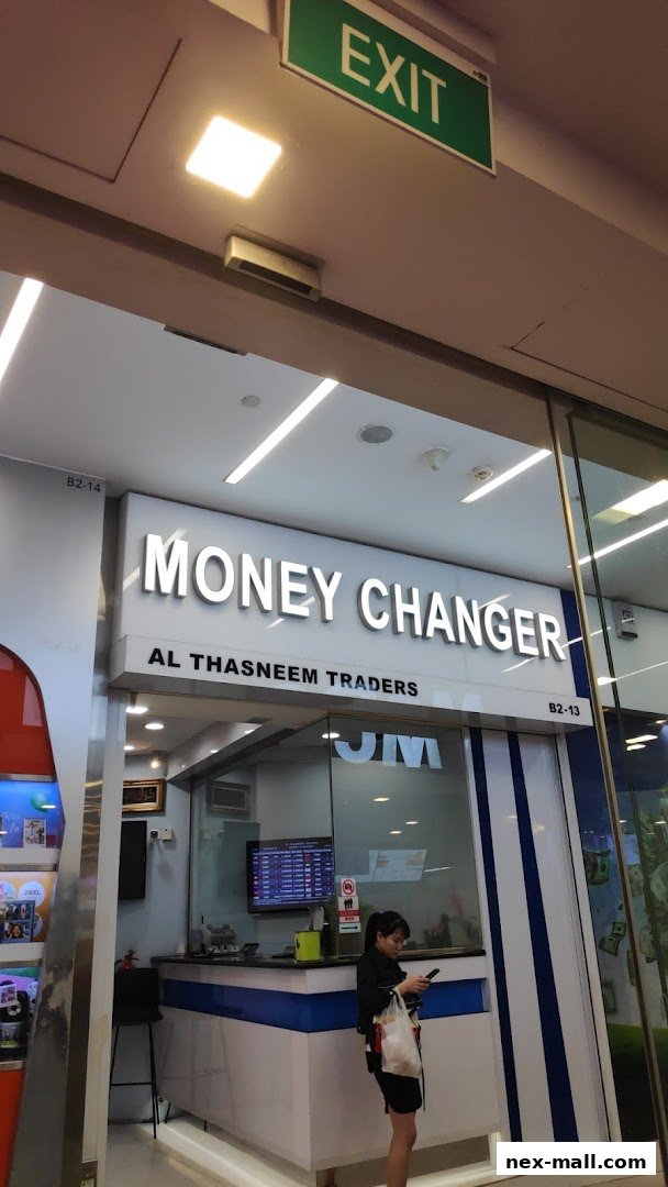 The entrance of AL Thasneem Traders Money Changer shop with a display of exchange rates.