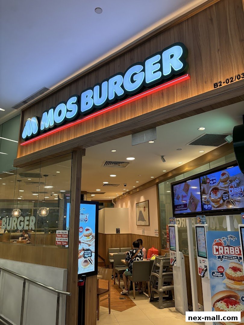 The exterior of a MOS Burger restaurant with its illuminated sign and digital menu displays.