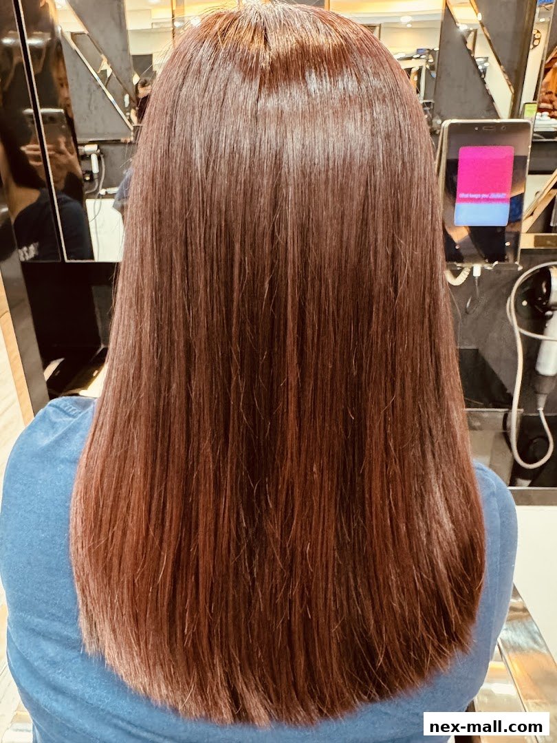 A person's back with long, straight, reddish-brown hair, showcasing a recent hair treatment.