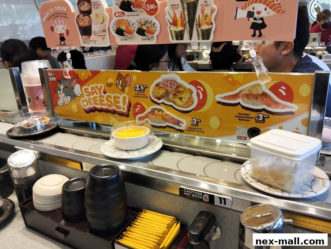 A conveyor belt sushi restaurant with various sushi dishes displayed and customers seated.