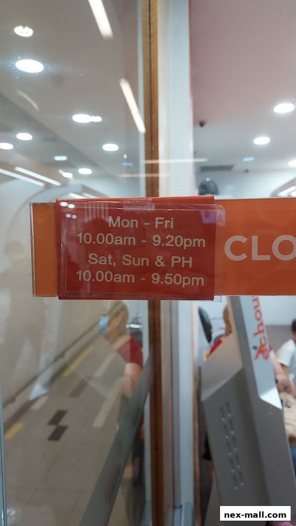 A sign displaying operating hours for EC House All Range Cuts, with reflections of the interior.