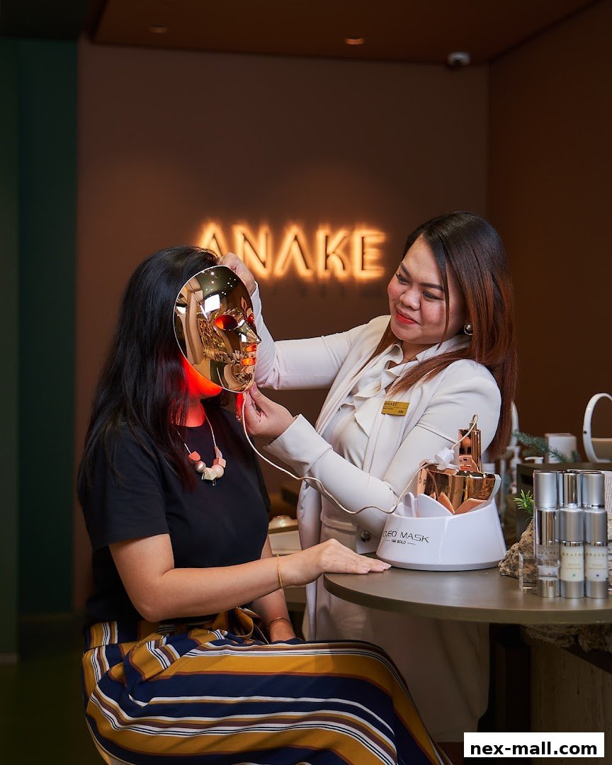 Aesthetician applying a gold LED mask to a client's face in a modern salon.