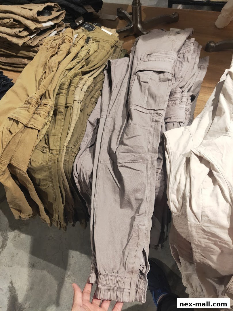 A selection of khaki and grey cargo pants neatly folded and displayed in a retail store.