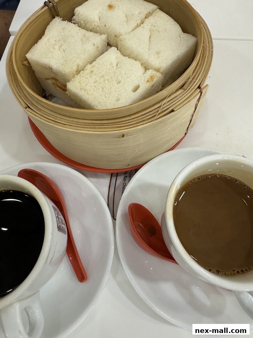 Two cups of coffee and steamed kaya toast served in a bamboo steamer.